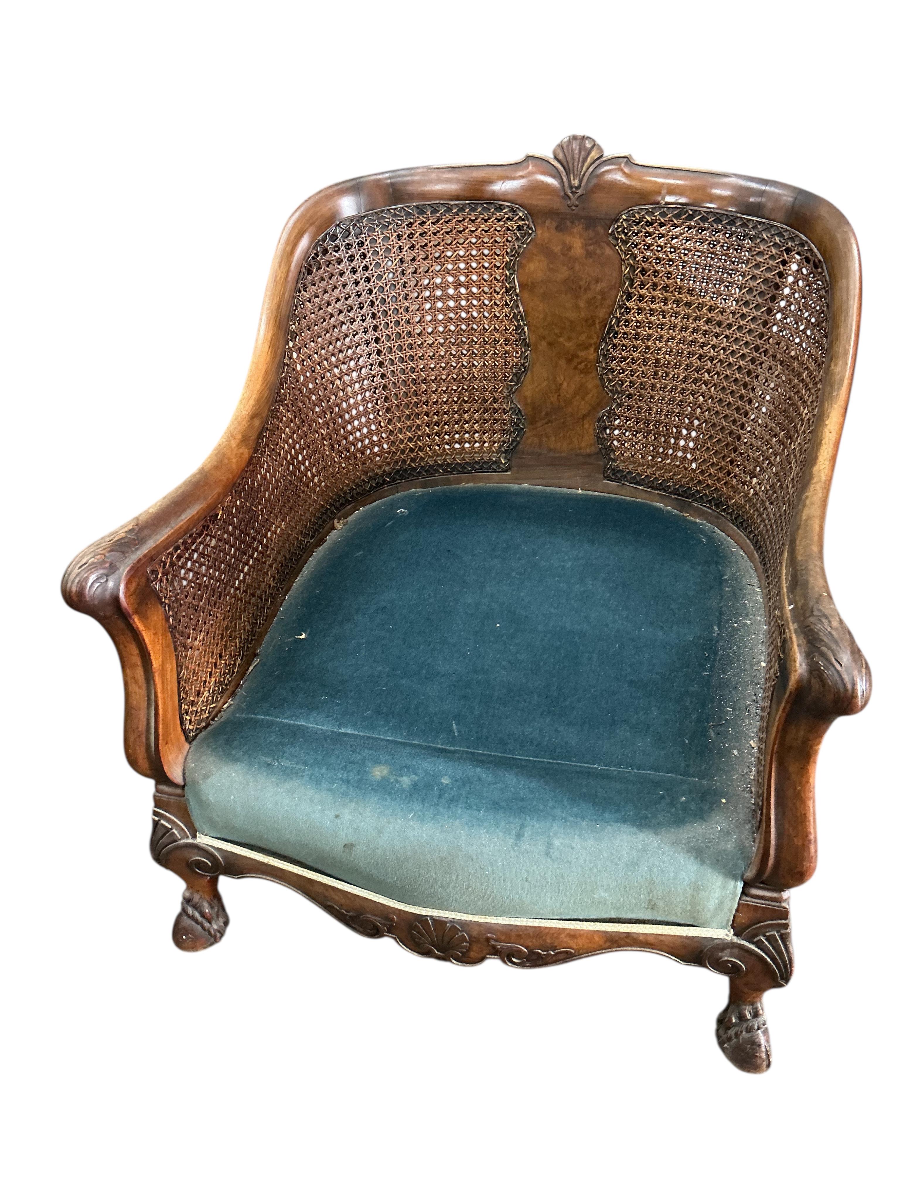An early 20th century carved walnut and double canework three piece bergère suite, cane in need of repair
